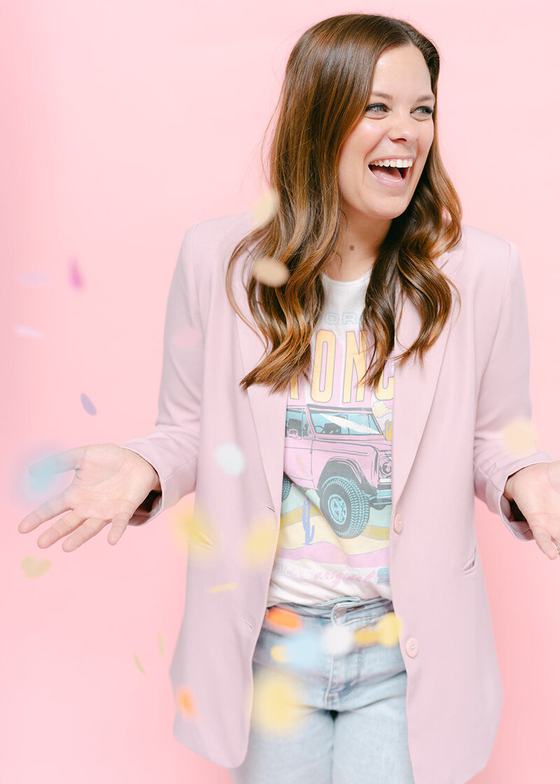 Courtney laughing in a blush blazer as confetti falls